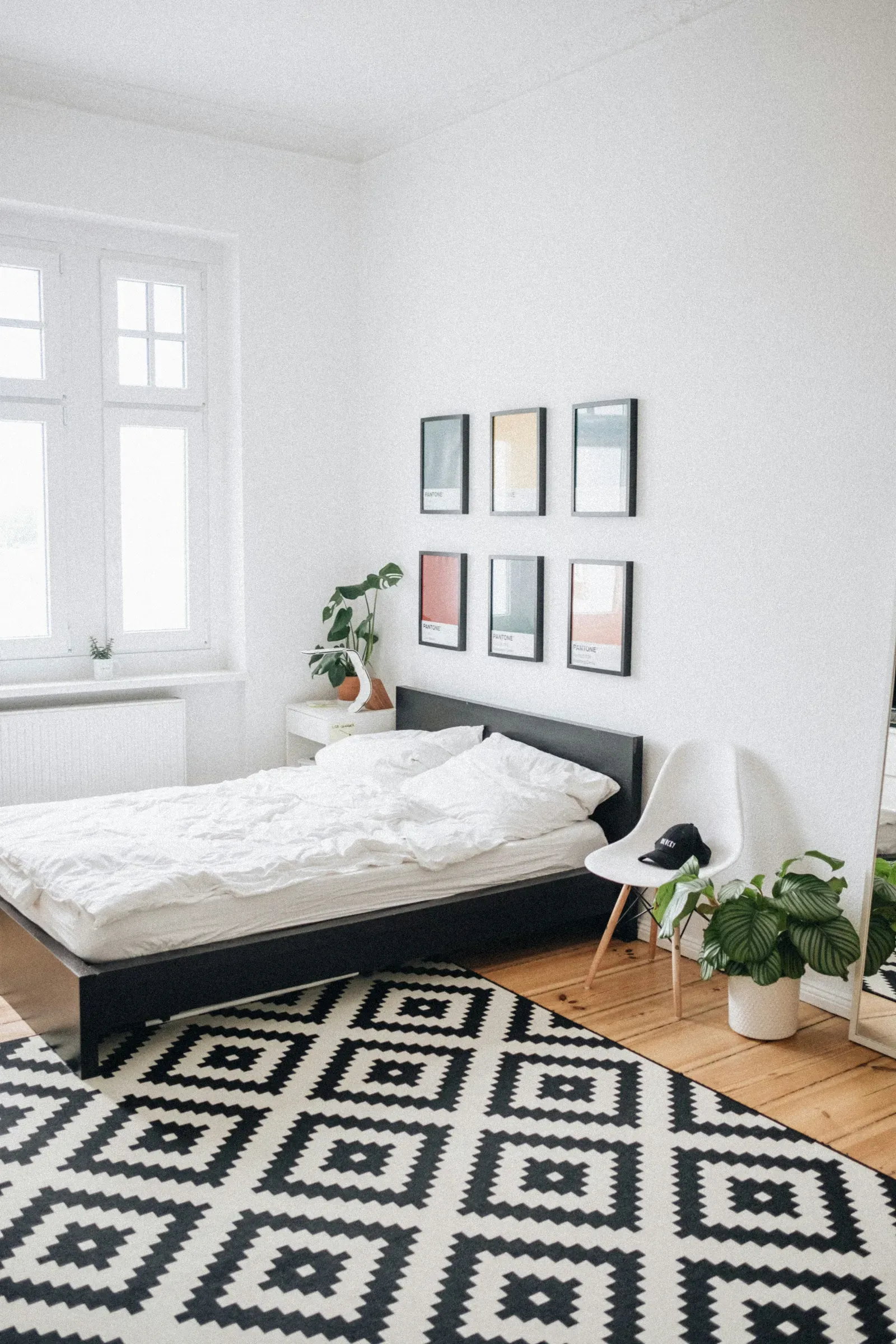 Layered neutrals in a bedroom — linen, warm wood and a single darker accent.