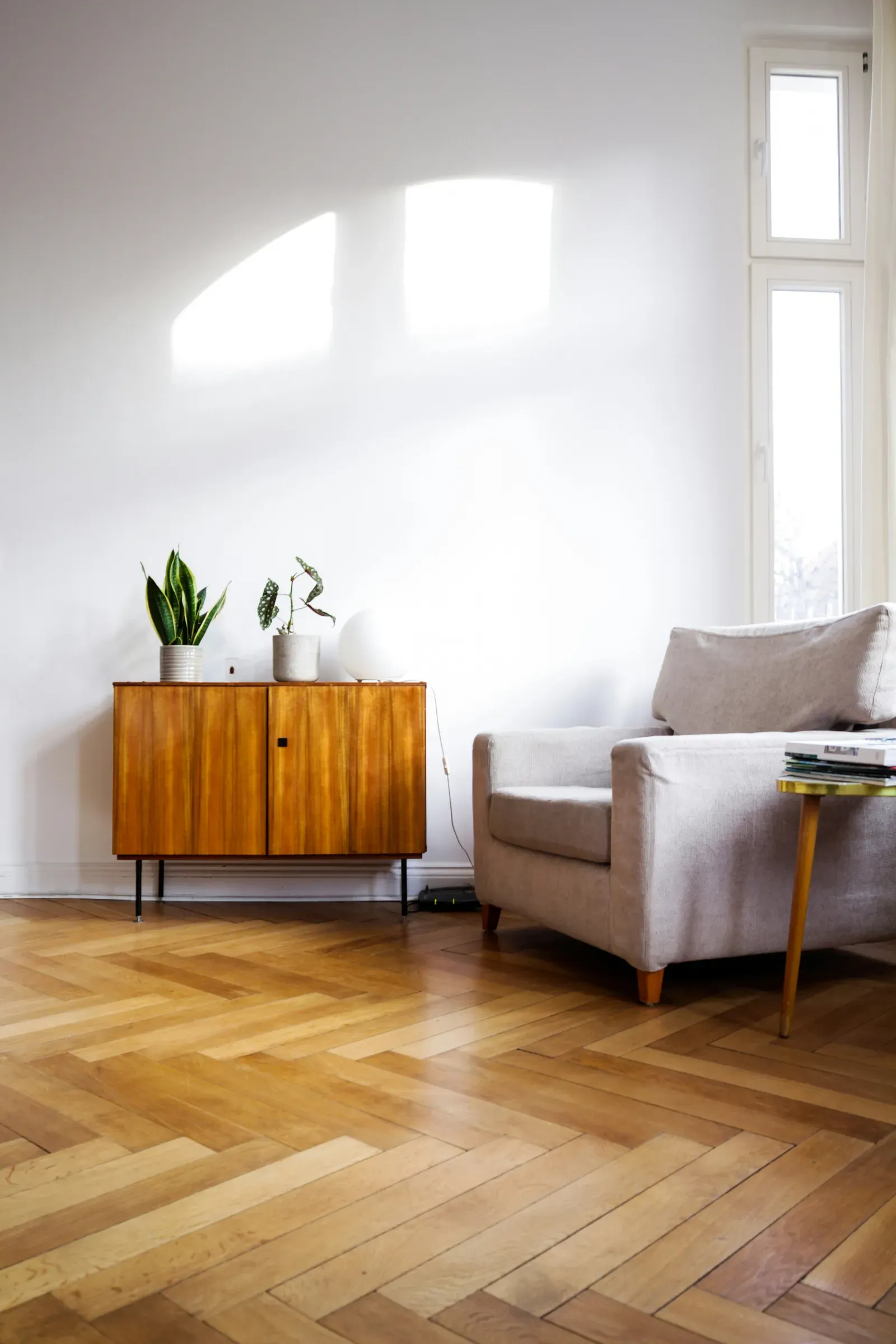 A quiet reading corner in warm neutrals — a linen armchair, a jute rug and a slim floor lamp.